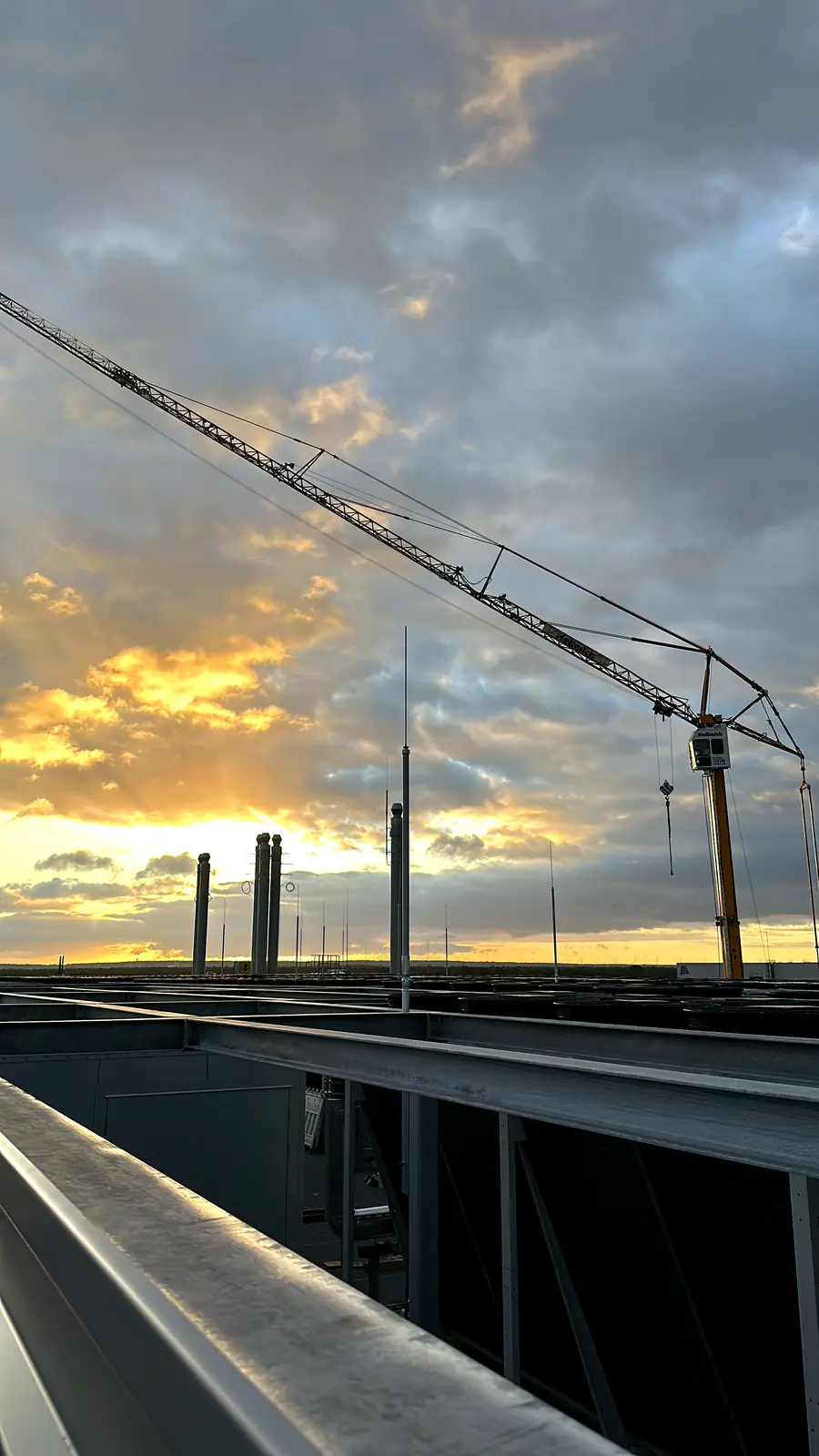 Crane on an industrial rooftop at sunset during installation works