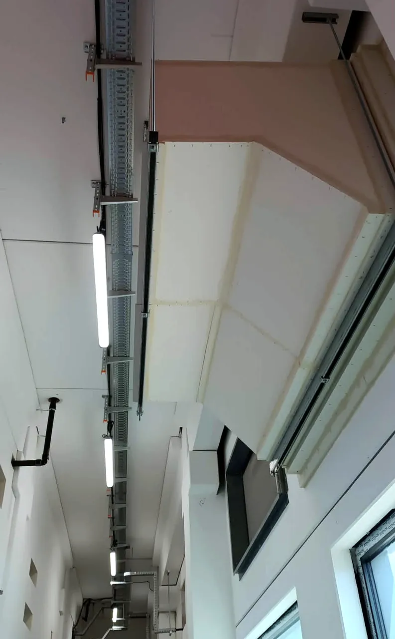 Fire-rated ventilation duct running along a building services corridor
