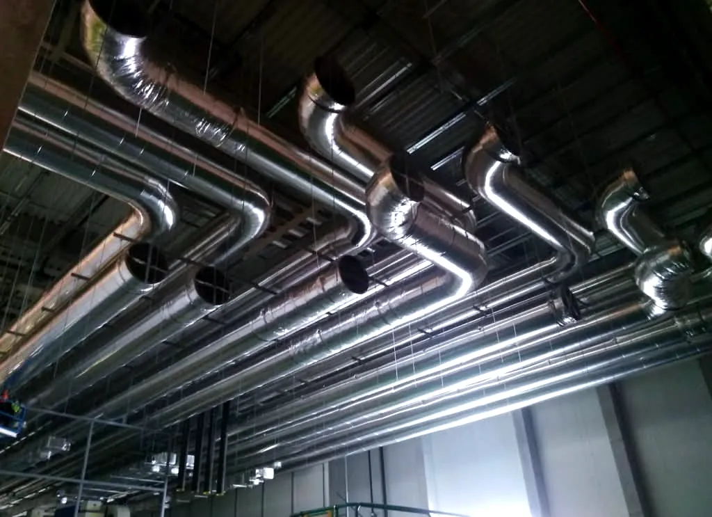 Insulated round industrial ductwork installed under a factory roof