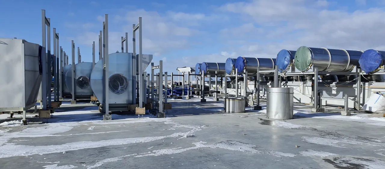 Large insulated ductwork mounted on steel supports in an industrial hall